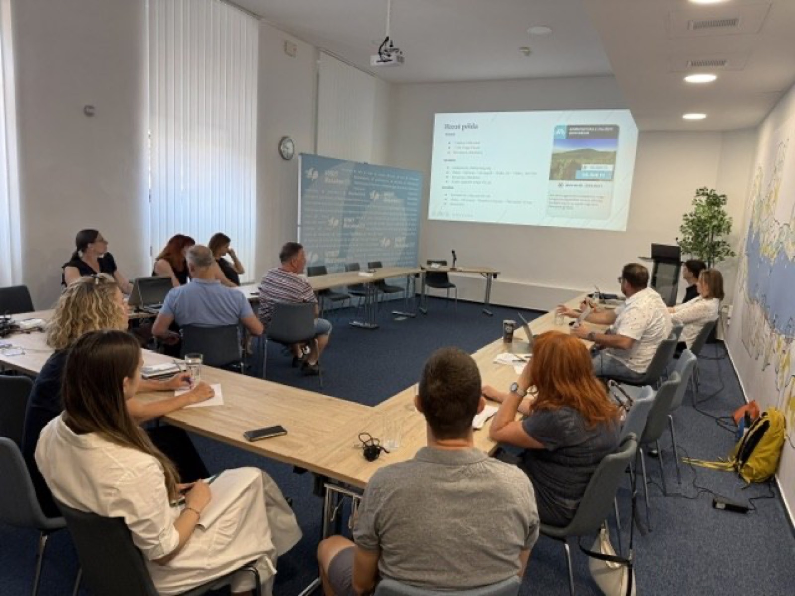 01: Adam Schmutz giving a talk on package pricing at VisitBalaton365's Keszthely training center; in the foreground the “Package creation” canvas with participants' notes. 02: The Keszthely training room with the Lake Balaton map on the wall; participants at the two-day workshop, the title slide on the screen. 03: Small-group work next to the VisitBalaton365 banner and the projected canvas template. 04: Participants following a package example on the projector. 05: The Keszthely training room from above, participants at the U-shaped tables in front of the Lake Balaton map wall. 06: A small group working together on the package canvas. 07: Participants working over the package-planning template at the long table. 08: A lively discussion in a four-person group. 09: Workshop participants in a small-group consultation with notes and a canvas. 10: Participants at the training room table in front of the Lake Balaton map.