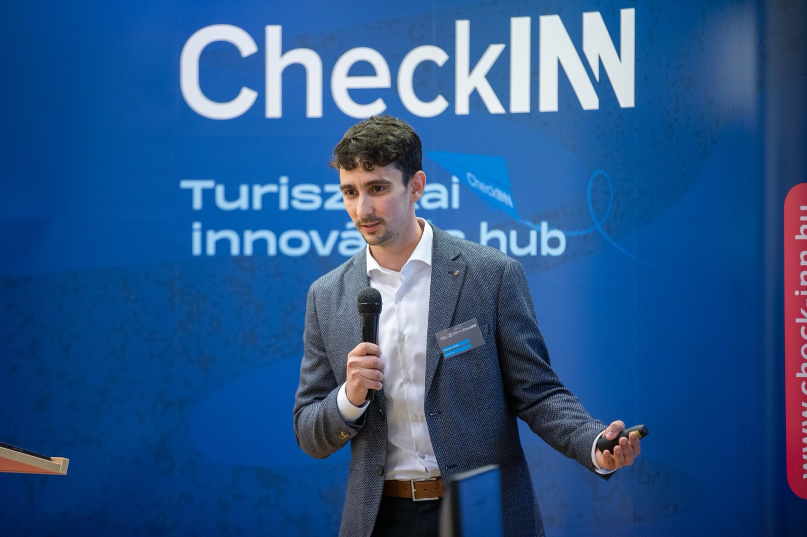 01: Adam Schmutz speaking with a microphone in front of the CheckINN banner, with the audience in the foreground. 02: Adam Schmutz mid-talk, the CheckINN Tourism Innovation Hub banner in the background. 03: Adam Schmutz presenting to the workshop audience in front of the CheckINN backdrop. 04: The full lecture hall with the audience; Adam Schmutz on stage by the CheckINN banner. 05: Round-table discussion: Adam Schmutz and the moderator in front of the METU backdrop. 06: The participants of the workshop's round-table discussion in front of the Budapest Metropolitan University banner. 07: Adam Schmutz during a professional conversation in a break of the event.